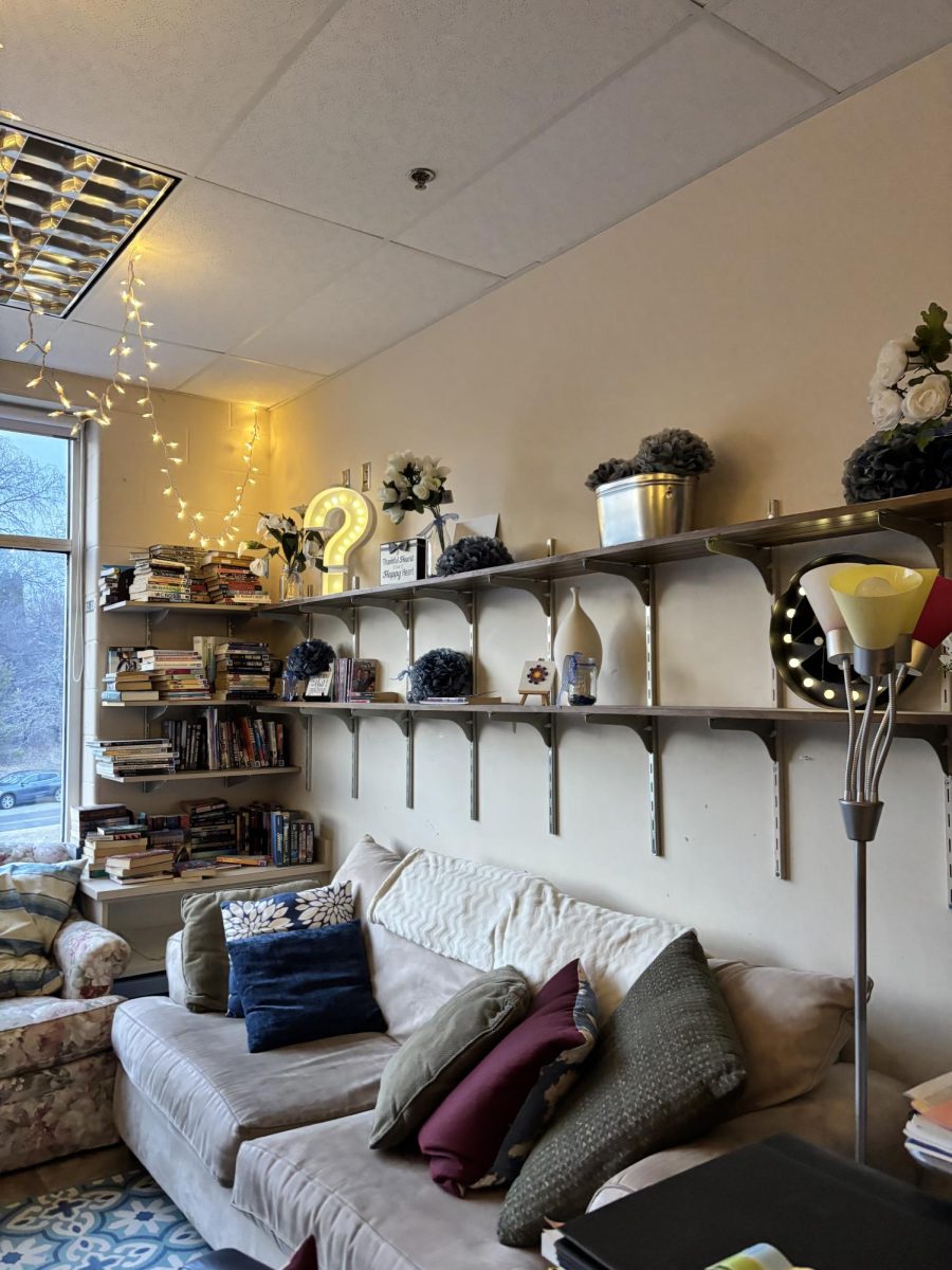 Photo of a dimly lit classroom on the second floor of MHS. The space has a more home-like feel due to a couch topped with many pillows and shelves housing uplifting knick-knacks. | Photo by Kaitlyn Anlauf
